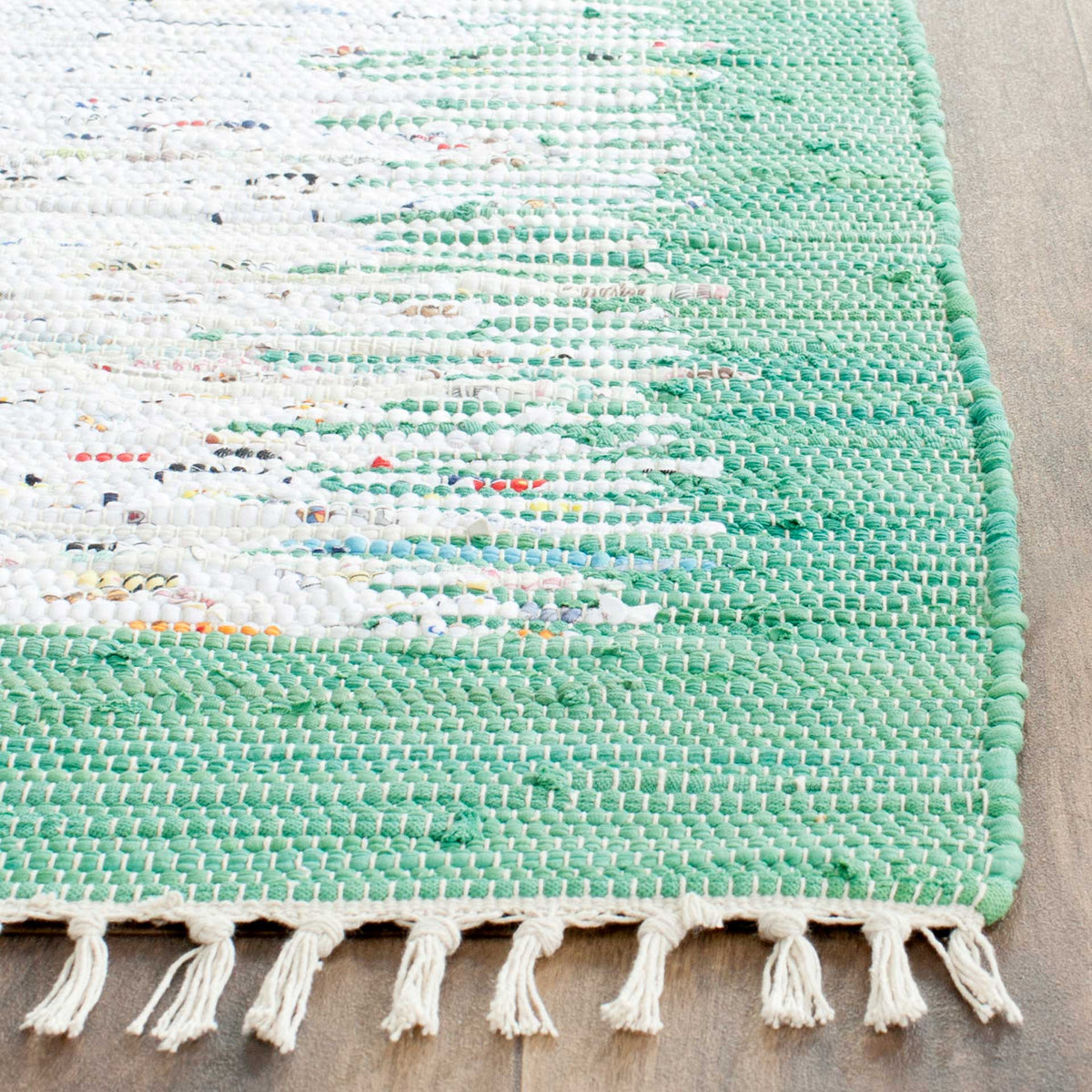 Sea green weaving blends into flecked ivory, with loose fringe along the end of the rug.