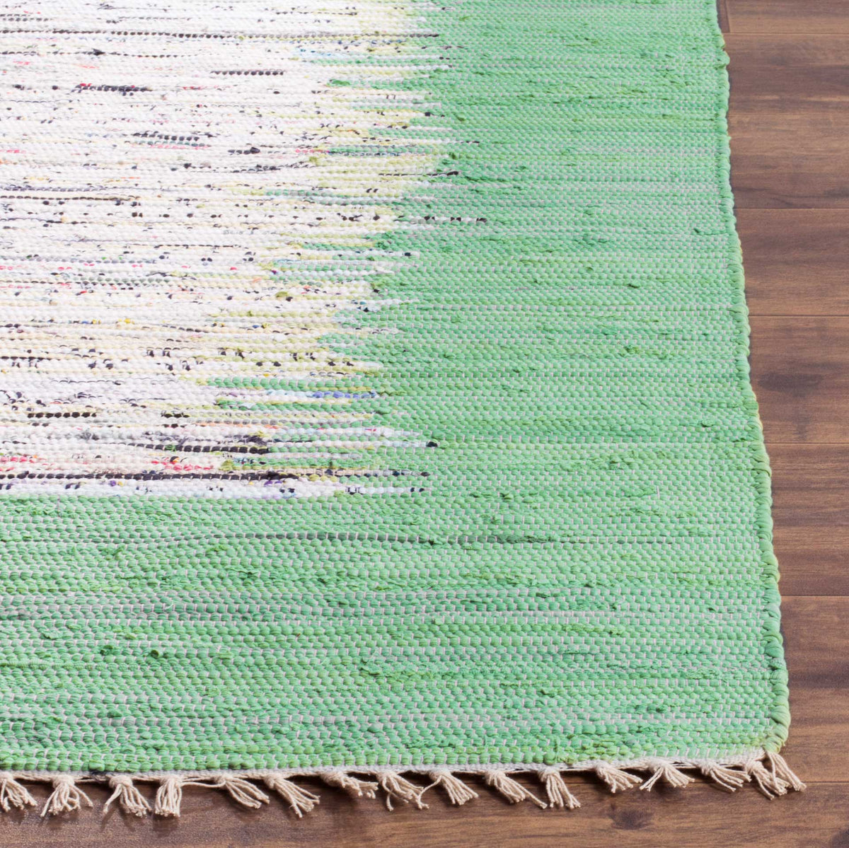 Sea green cotton threads meet colorful ivory flecks at a fringed, handwoven rug corner.