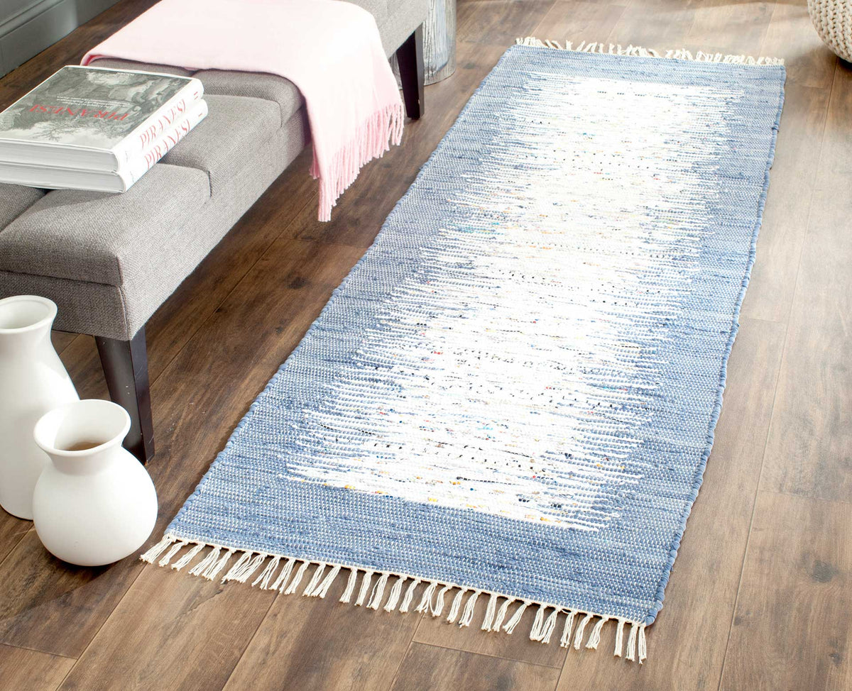 The fringed blue and ivory runner adds an airy, textured accent beside a gray upholstered bench.