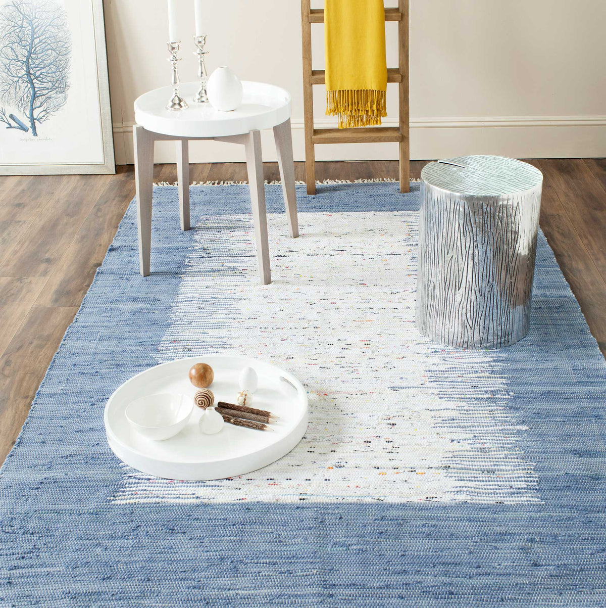 A blue-framed ivory rug adds woven texture and quiet color beneath contemporary accent tables.