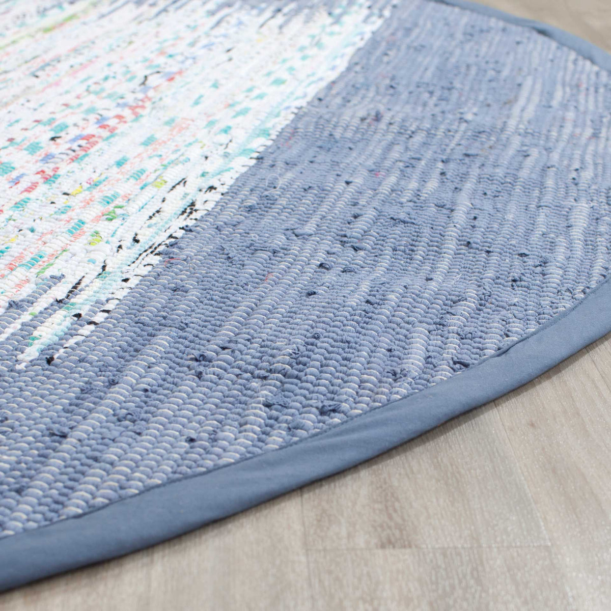 Textured blue cotton weave and a bound edge frame streaks of ivory and colorful threads