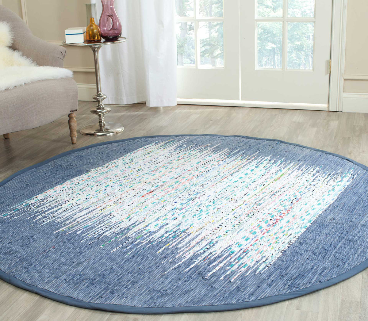 A round ivory-and-blue rug adds a woven abstract accent beside a cozy chair