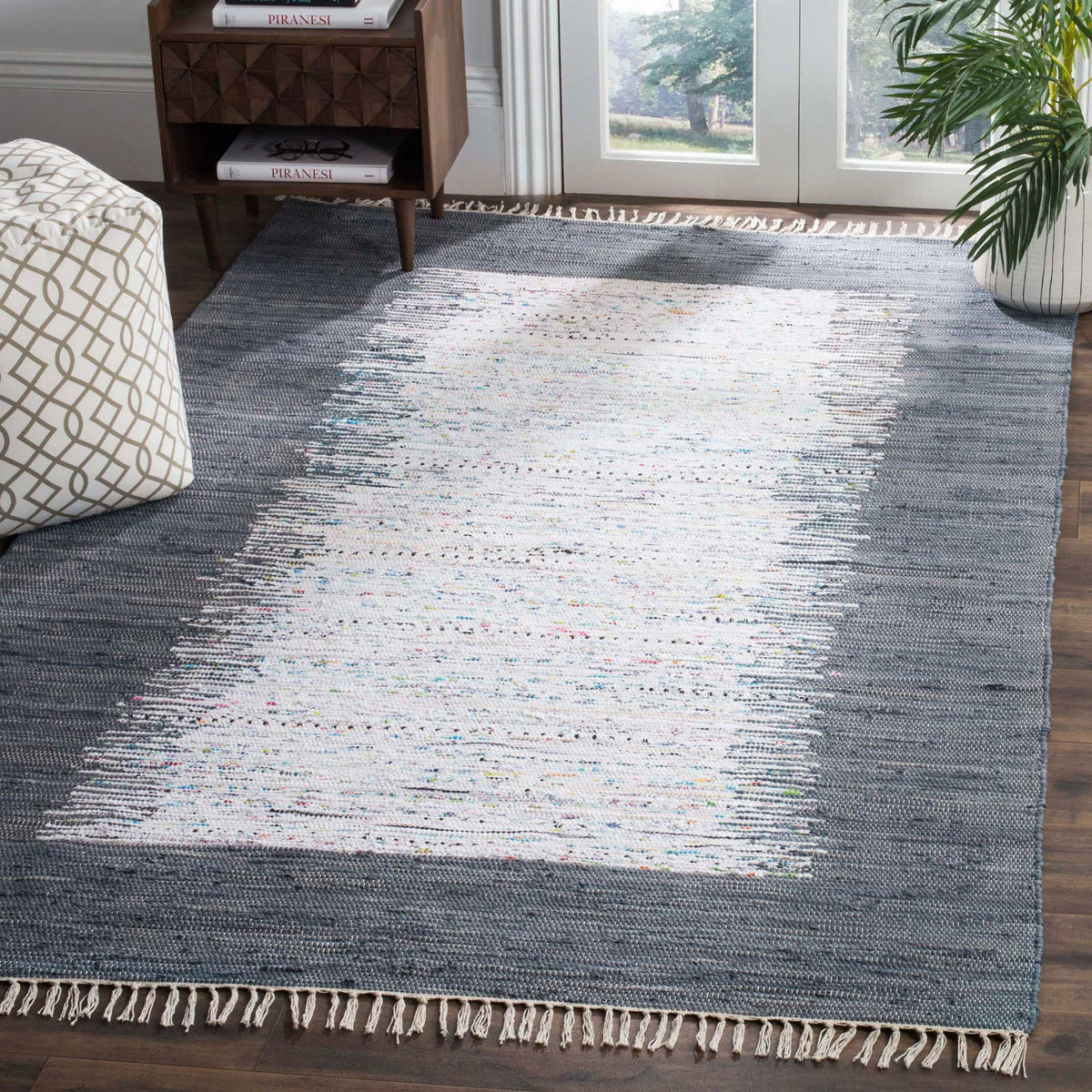 A gray-bordered ivory rug softens a bright seating space with handwoven texture and end fringe.