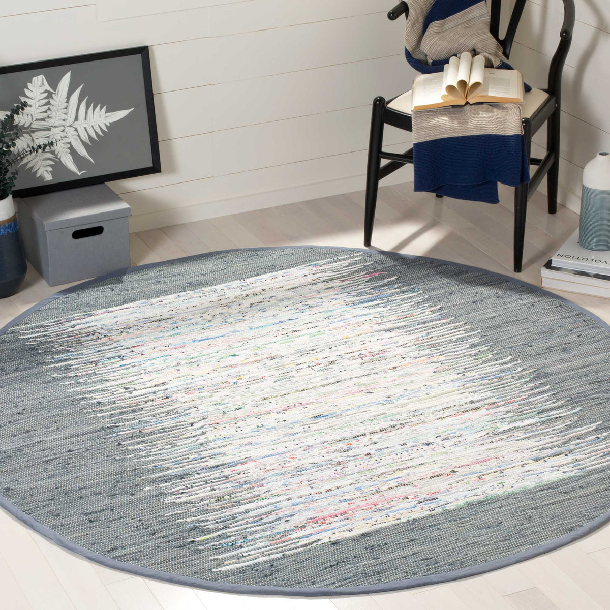 An ivory abstract center with colorful flecks softens the gray border of this round rug