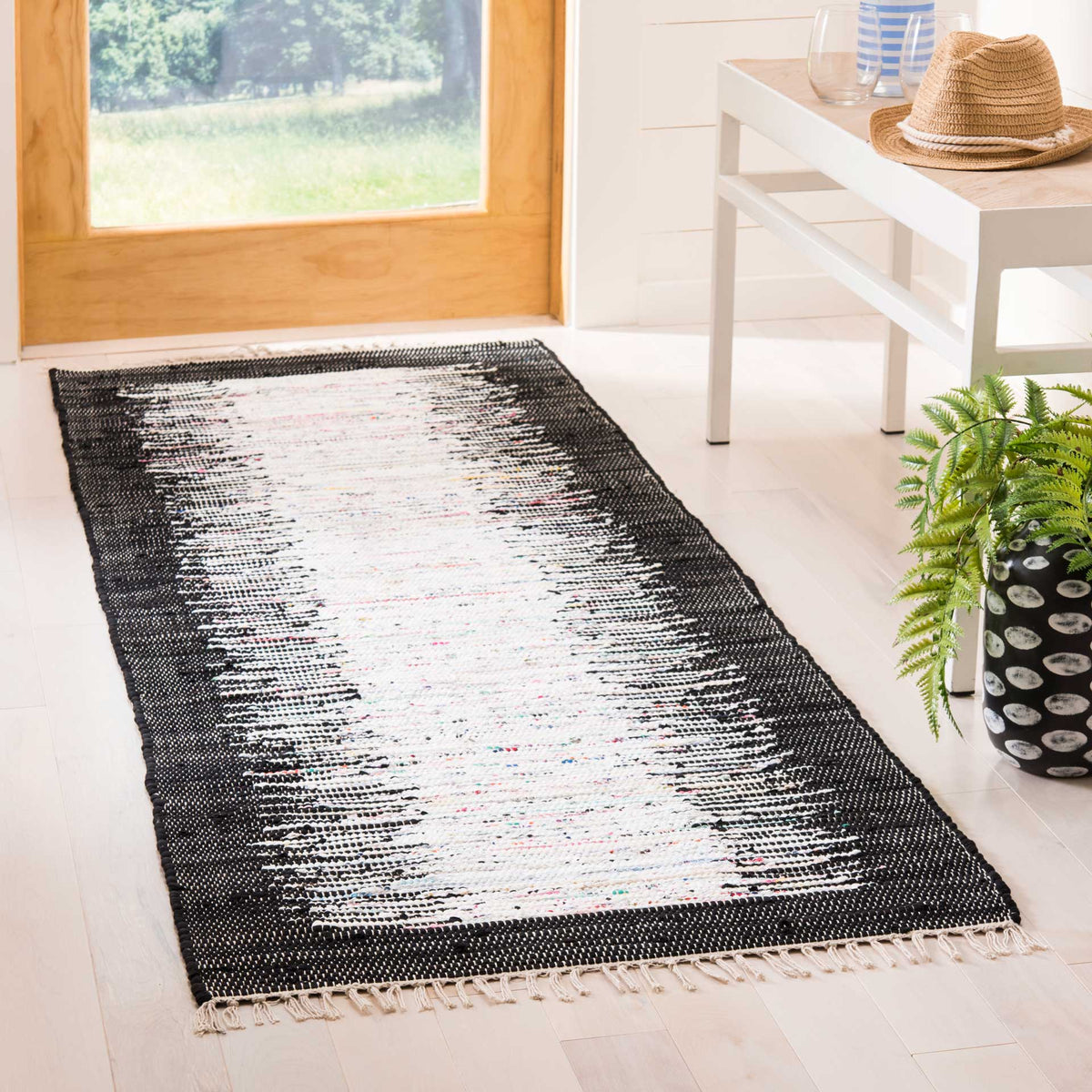 A black border frames the ivory runner, adding crisp contrast to a light-filled entryway.
