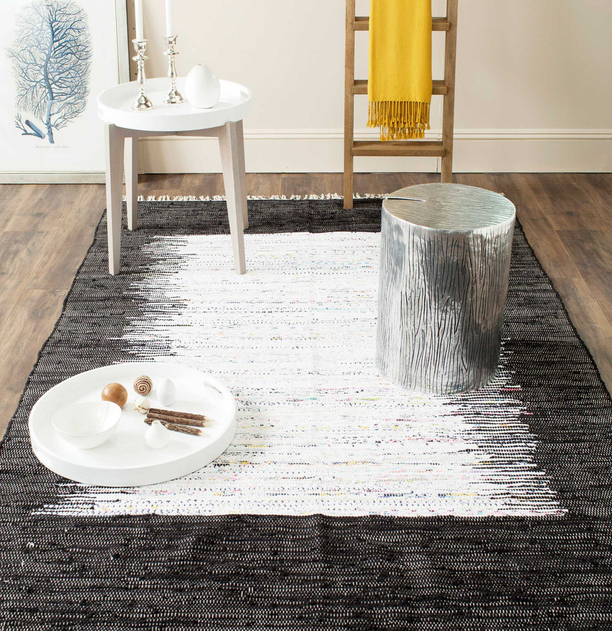 The fringed black and ivory cotton rug anchors a bright space with a bold, painterly center.