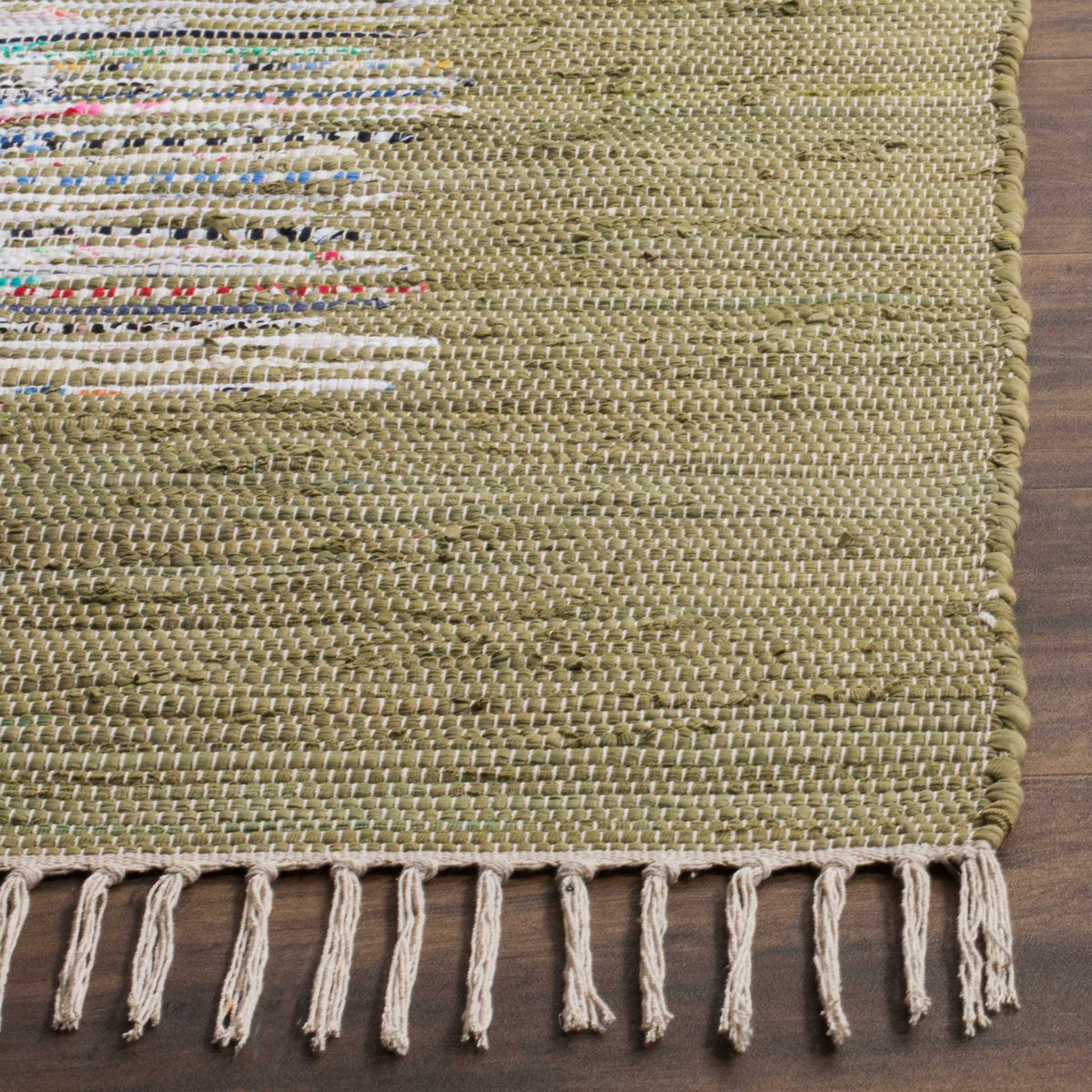 Pale fringe and varied olive cotton threads highlight the rug's richly tactile woven corner.