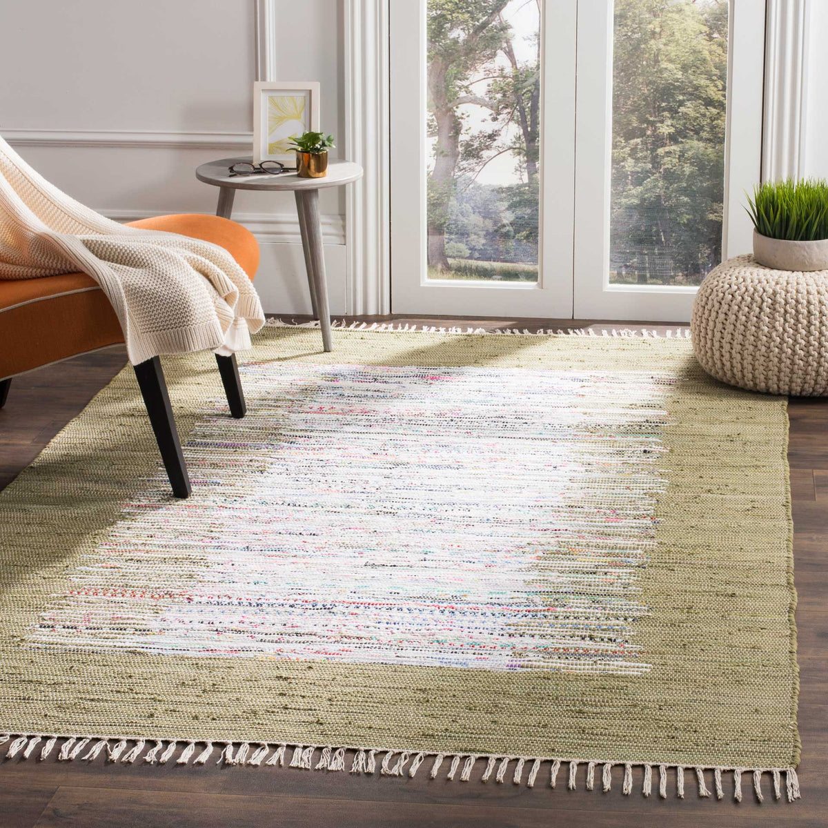 An olive-framed ivory rug brings earthy color and handwoven character to a sunny seating area.