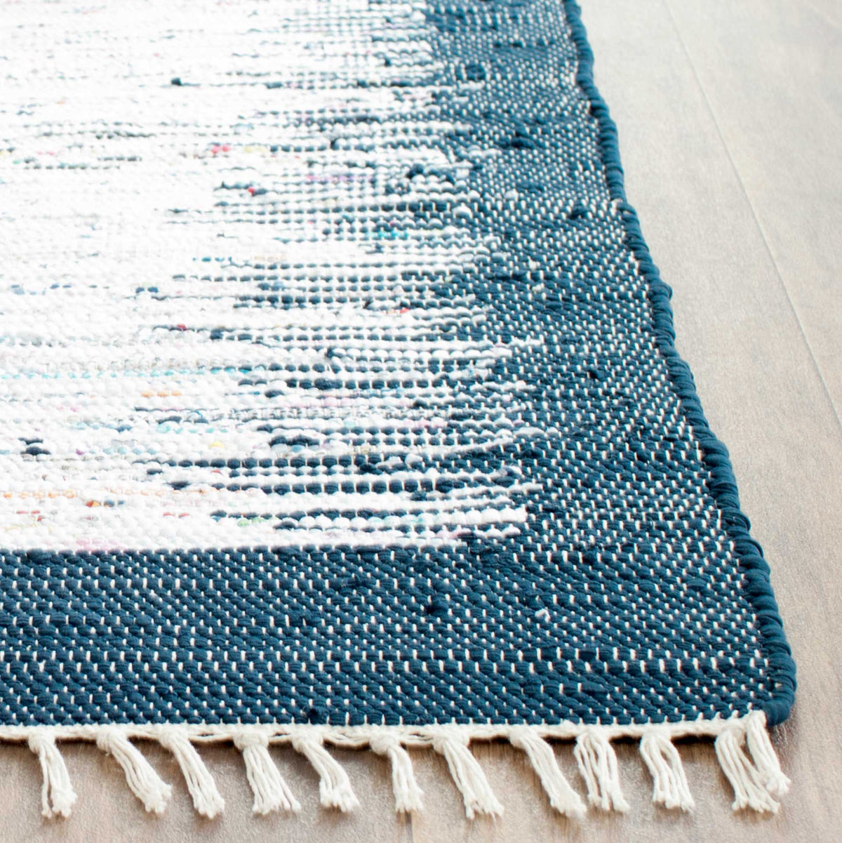 Deep navy weaving fades into ivory streaks, while soft cotton fringe finishes the end.