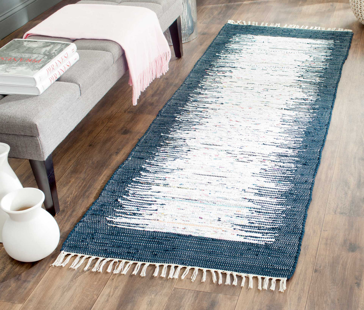 Navy edges sharpen the ivory runner's abstract weave against warm wood flooring.