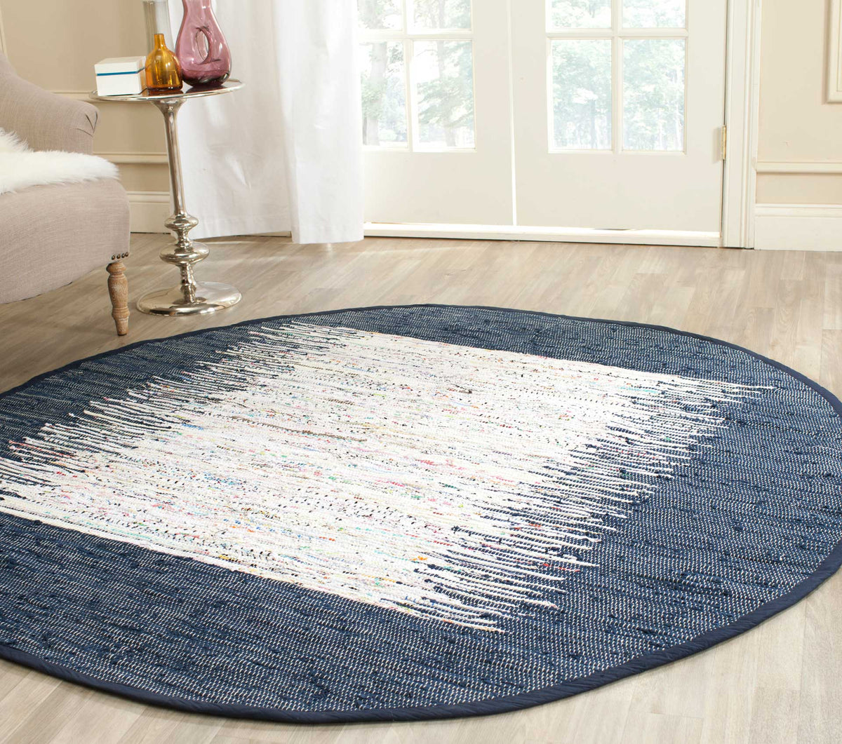 A bold navy border gives this round ivory rug striking contrast in a bright living space