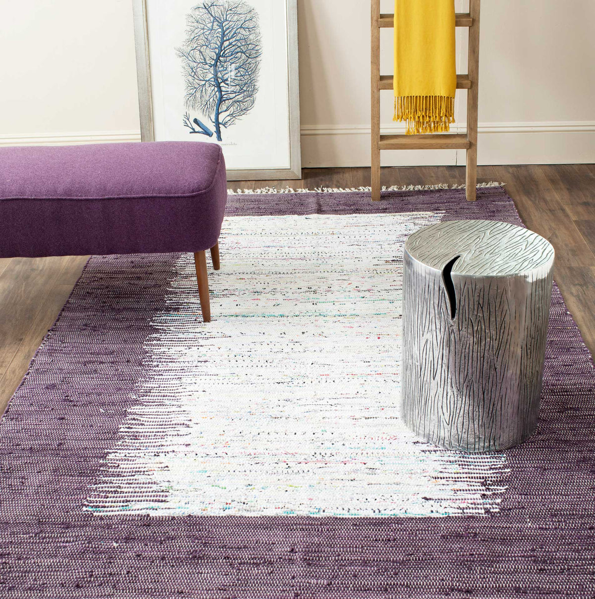 A purple-bordered ivory rug brings soft contrast and handwoven charm beneath modern accent furniture.