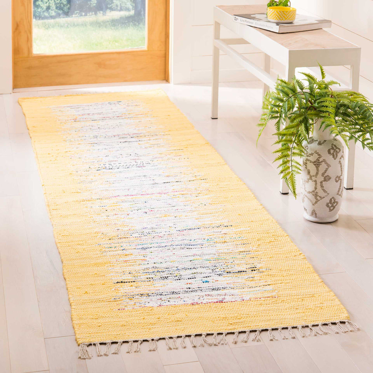 A yellow and ivory runner adds sunny color and textured warmth beside a white entryway table.