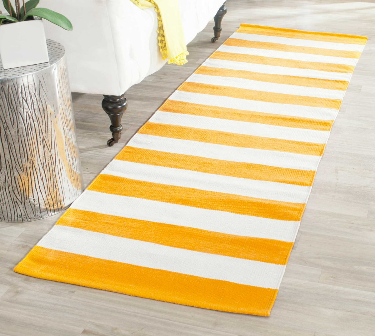 Sunny yellow and ivory stripes brighten the floor beside a white upholstered bed.