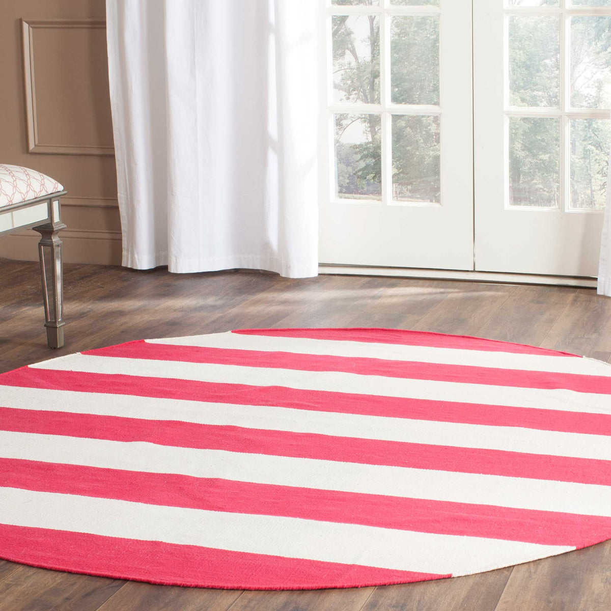 Bright red and ivory stripes enliven this round rug against rich wood floors.