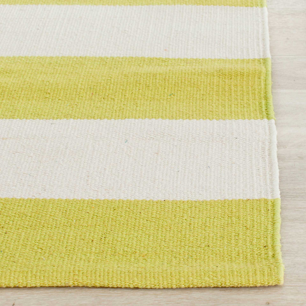 A woven cotton texture and clean edge complement the pale green and ivory stripes.