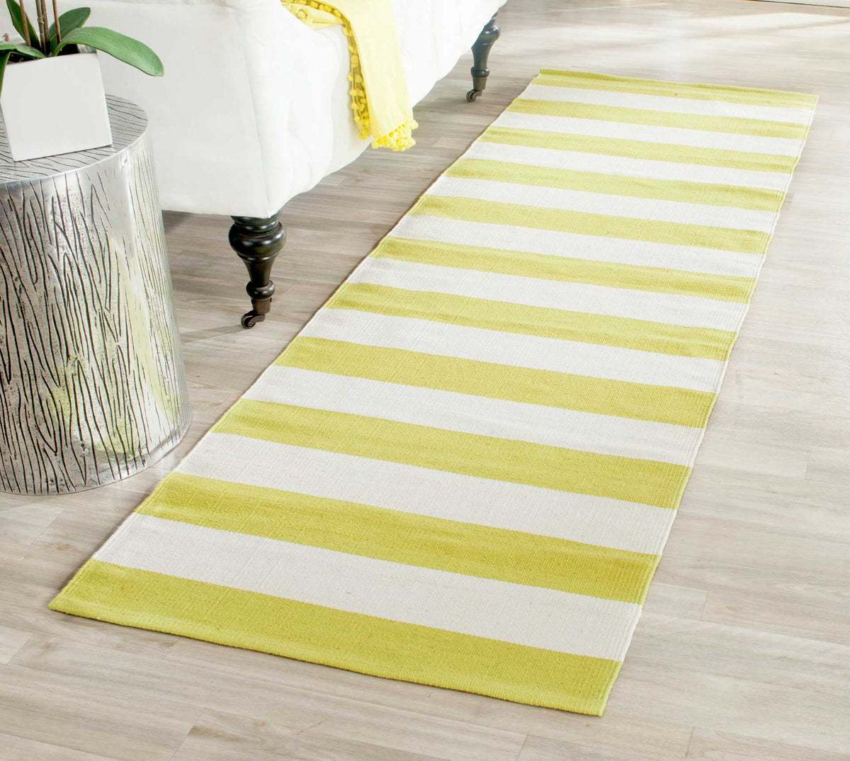 Soft green and ivory stripes add fresh color beside a white upholstered bed.
