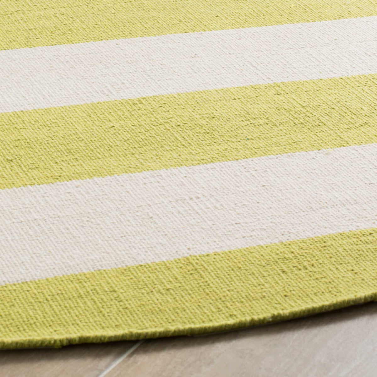 A finished curved edge highlights the textured cotton weave and light green and ivory bands.
