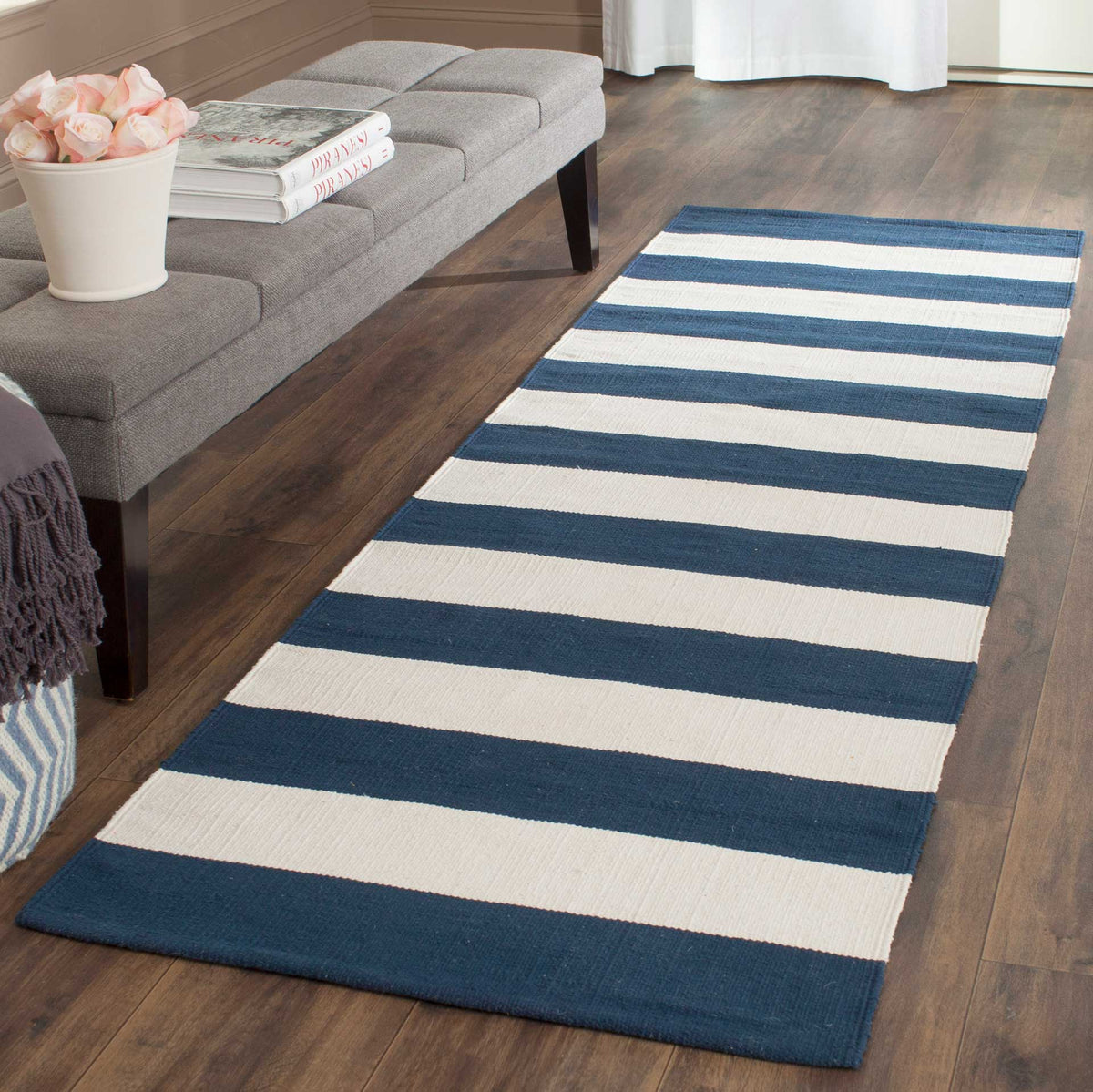 A navy and ivory cotton runner brings a coastal accent alongside a gray upholstered bench.