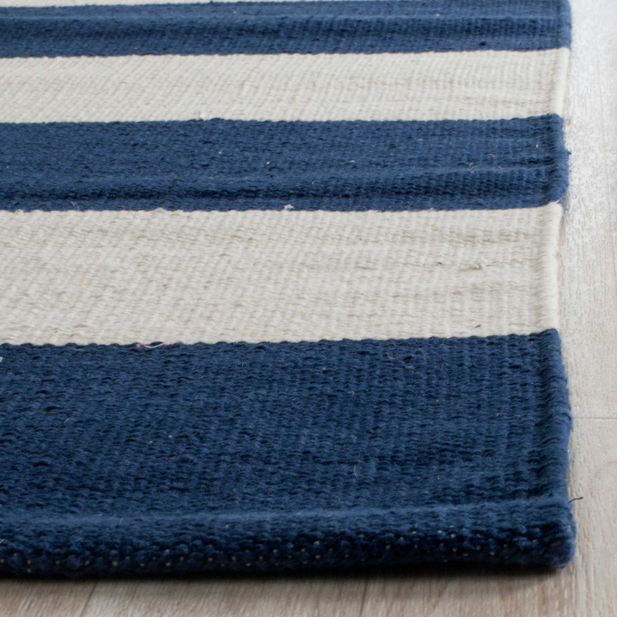 Dense navy and ivory weaving meets a neatly finished corner for a crisp, tactile look.