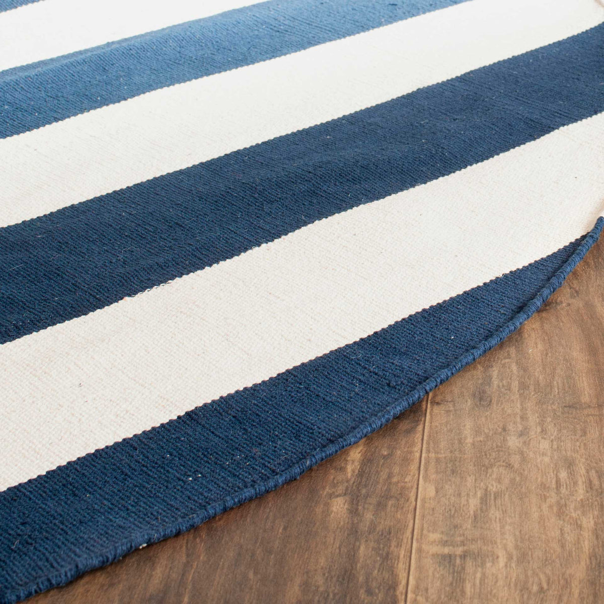 A navy-bound curved edge frames the textured cotton weave and clean ivory bands.