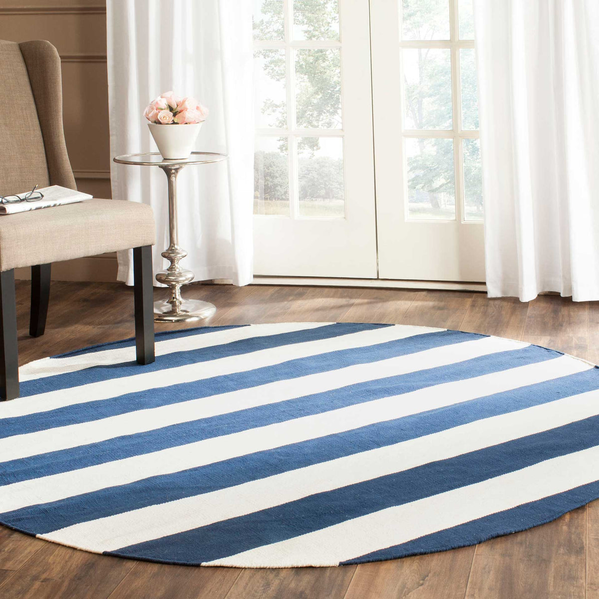 Wide navy and ivory bands make this round rug a crisp accent beside a neutral armchair.