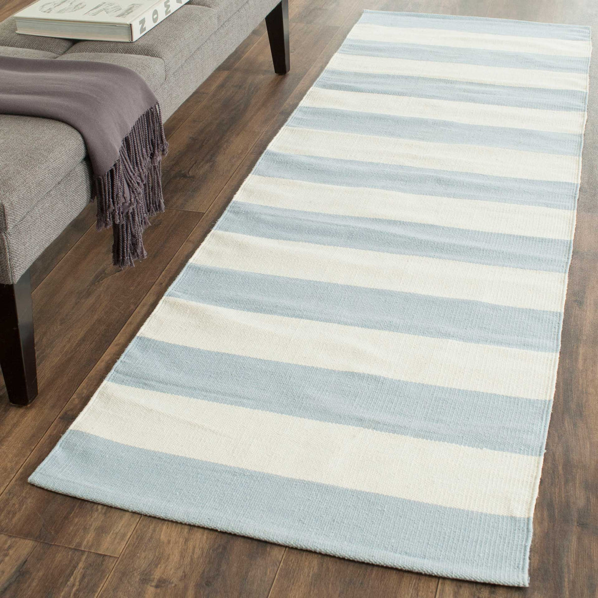 Pale blue and ivory stripes soften the floor beside a gray upholstered bench.