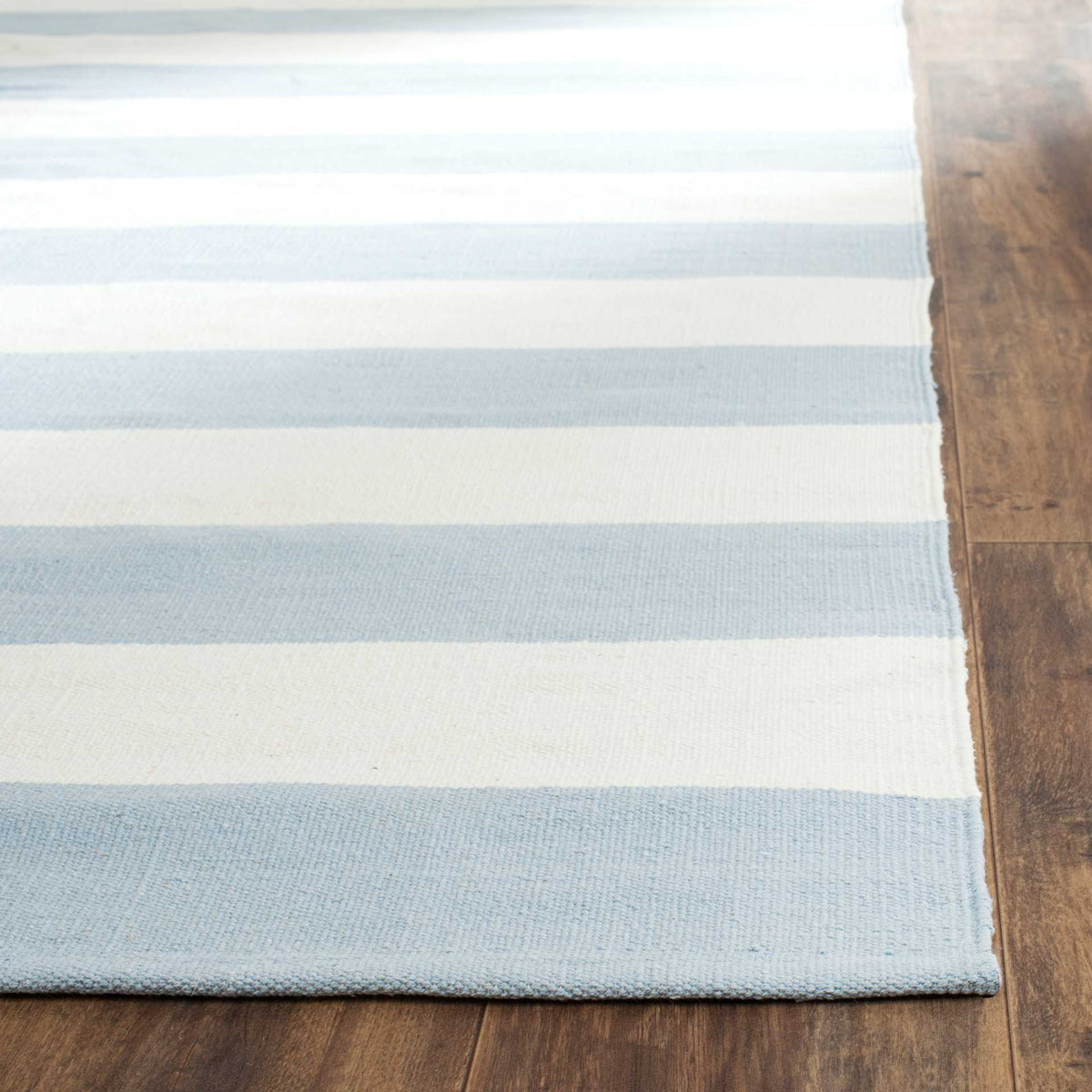A subtly textured weave and neat edge finish frame sky blue and ivory stripes.