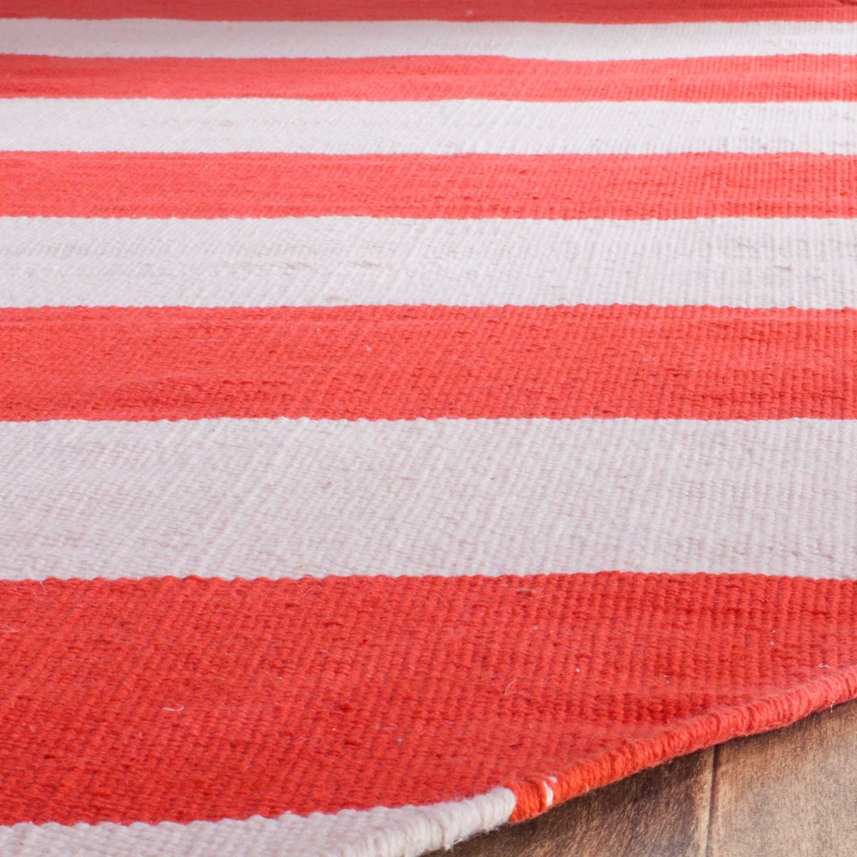 Red-orange and ivory cotton stripes reveal a tactile weave and a neatly bound edge.