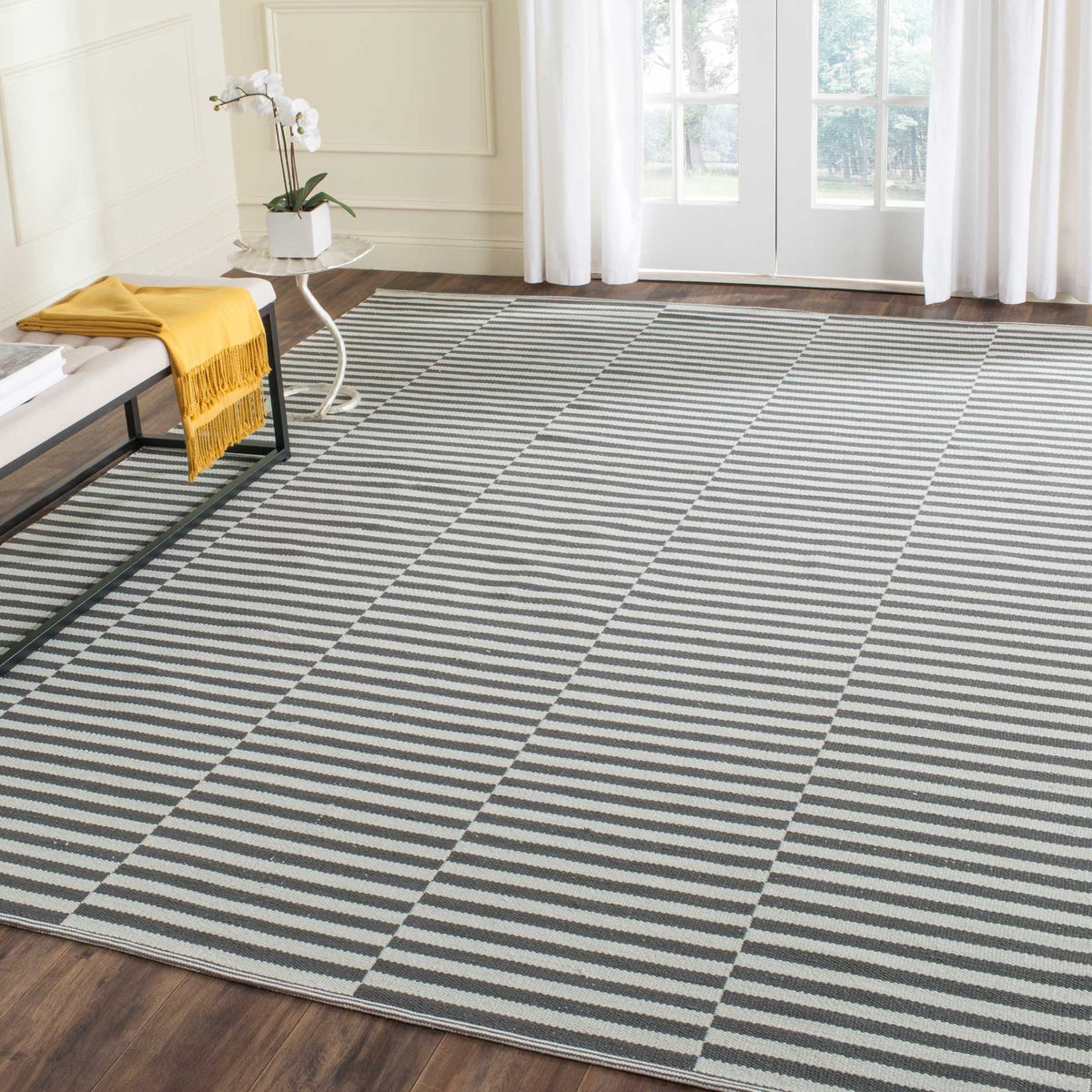 A broad gray and ivory striped rug adds subtle structure to a bright, relaxed room.