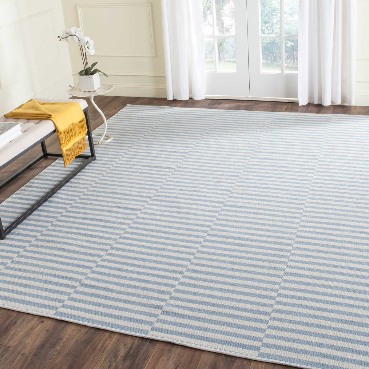 An ivory and light blue striped rug lends airy color to a warm wood-floored room.