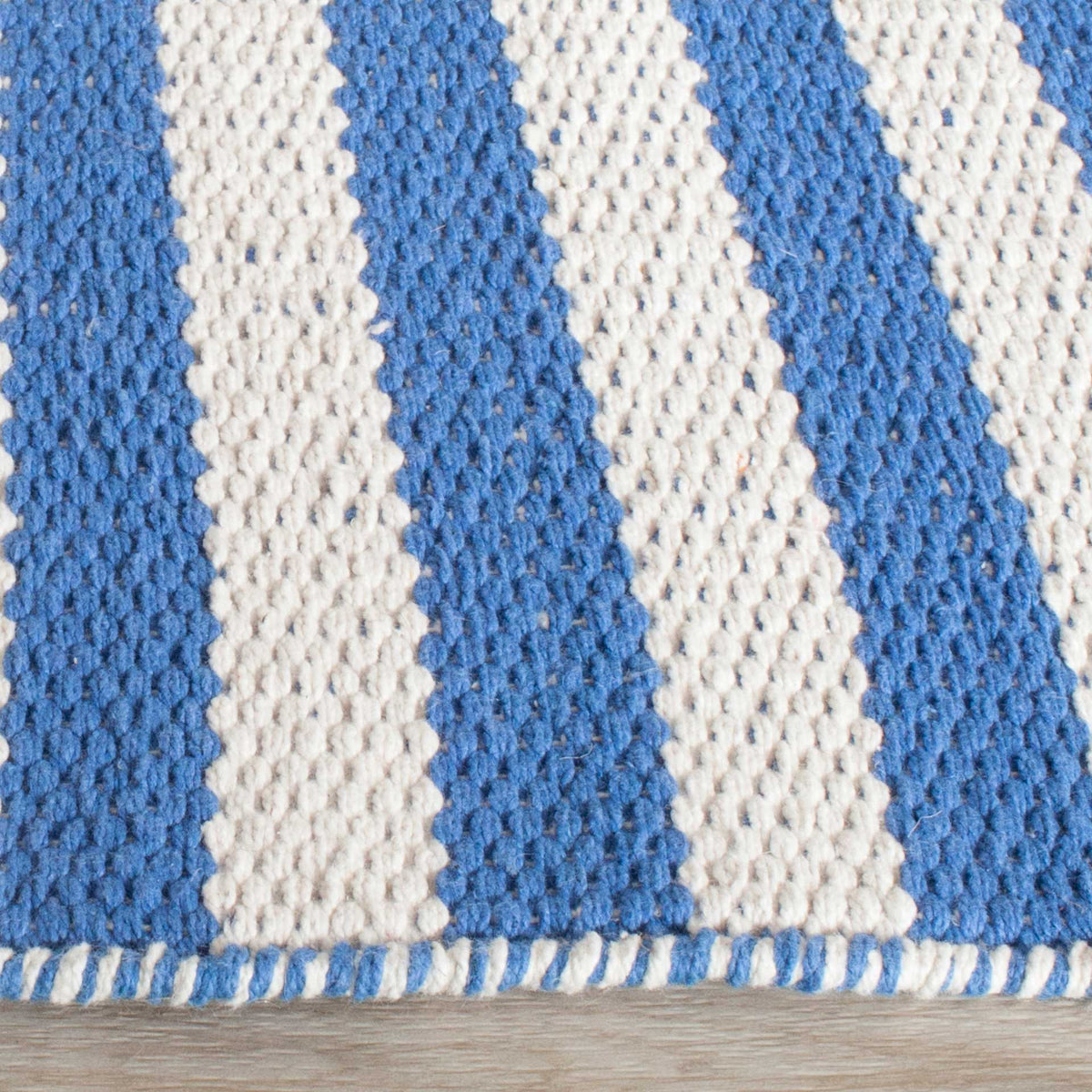 Blue and ivory cotton yarns meet a neat, two-tone bound edge