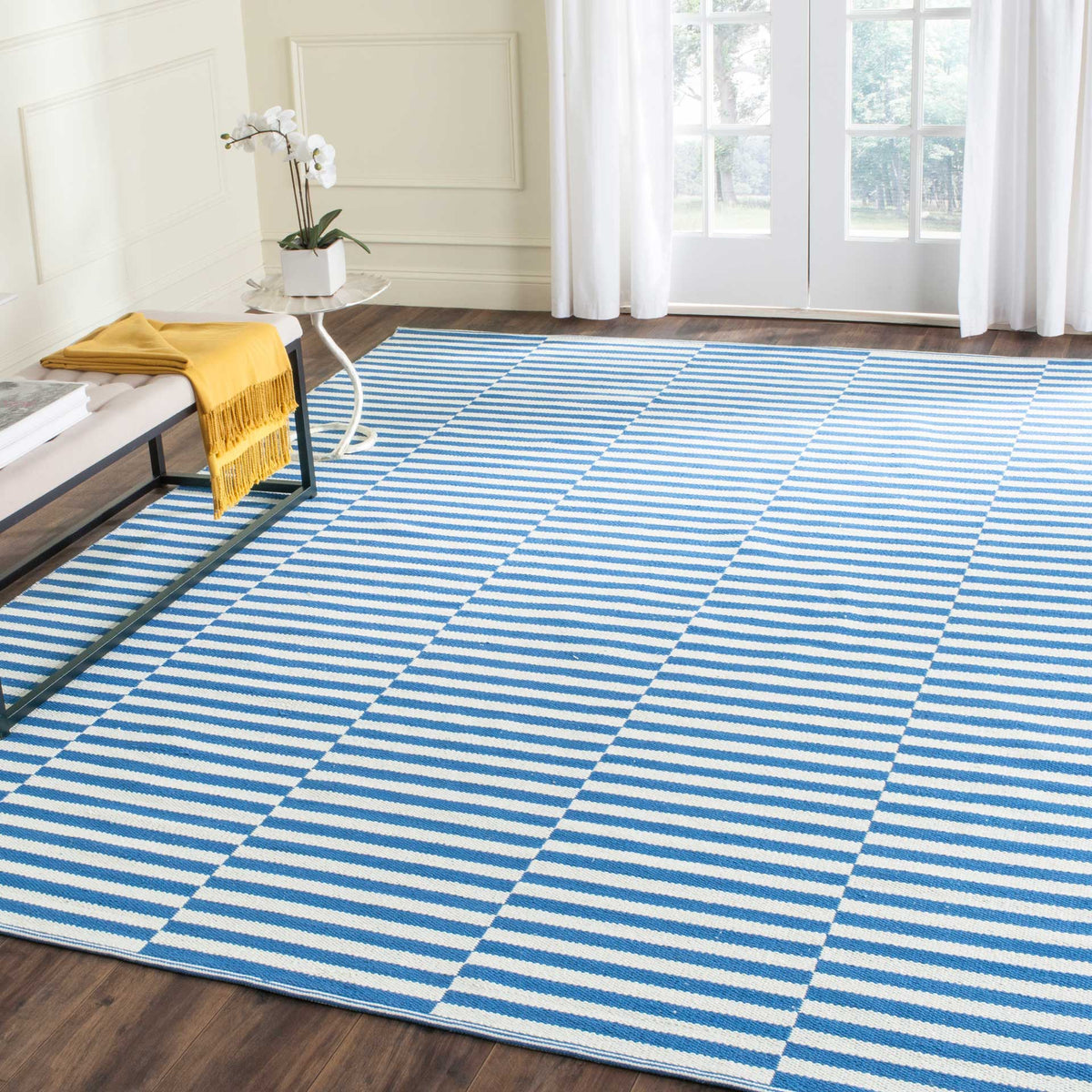 A blue and ivory striped rug brings an energetic coastal accent to a light-filled room.