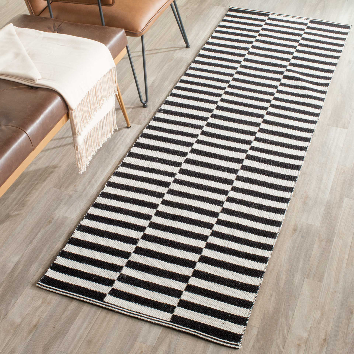Graphic black-and-ivory stripes add a striking accent to this slender cotton runner