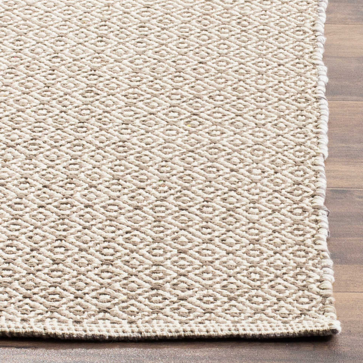 Tightly woven ivory and gray motifs meet a clean bound edge on this cotton rug.
