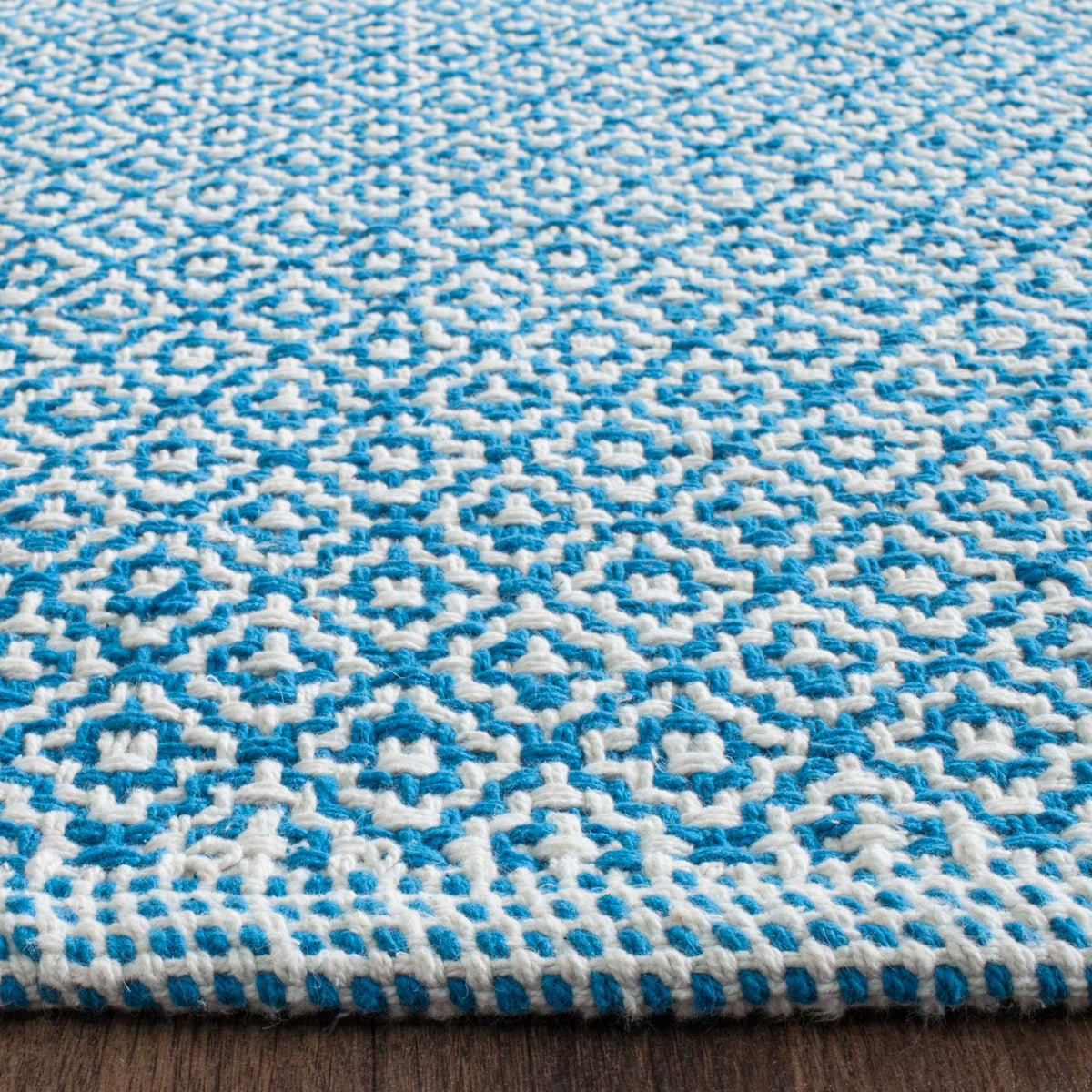 Raised blue and ivory diamonds extend to the tightly finished edge of this handwoven rug.