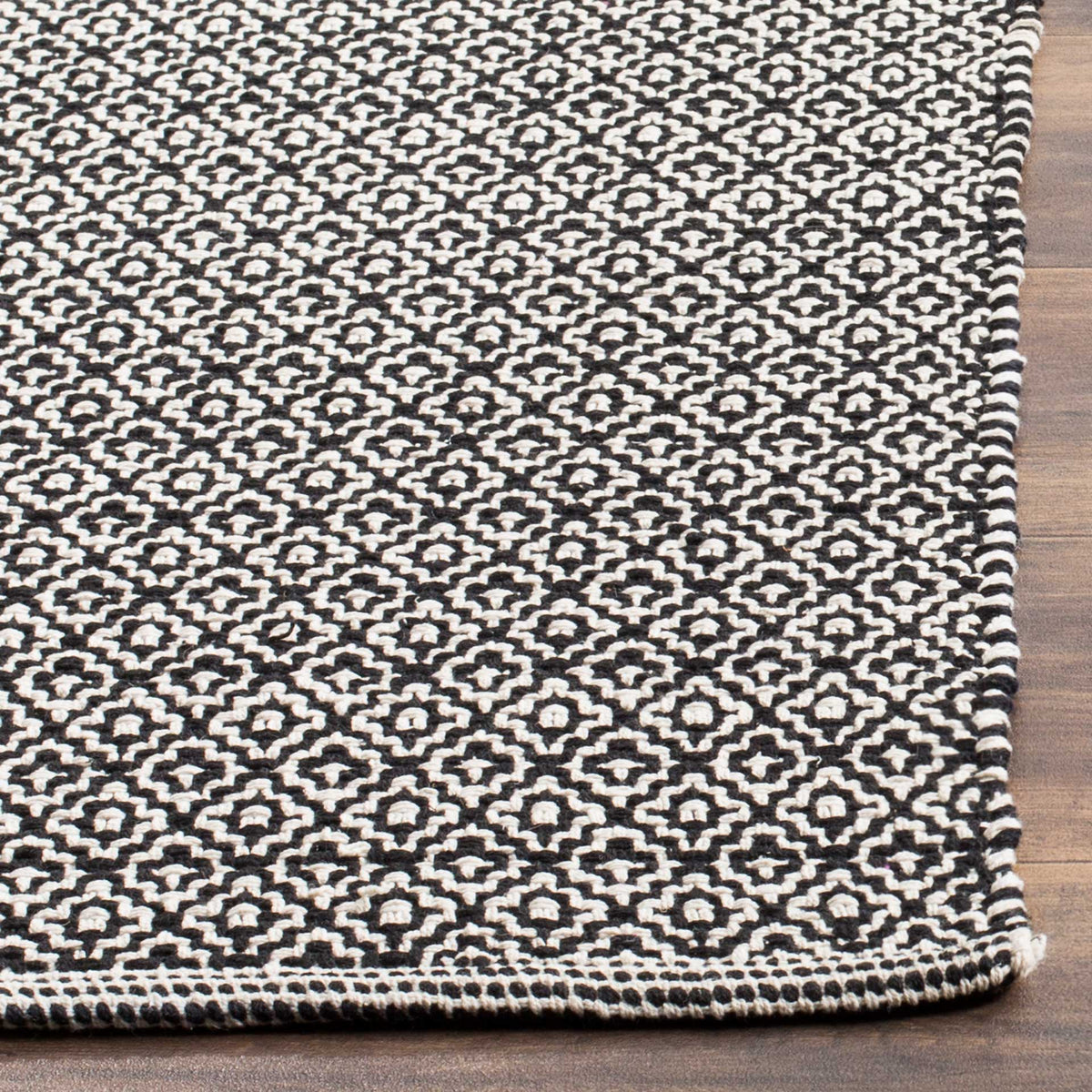 Black and ivory woven diamonds meet a neatly bound edge on this low-profile cotton rug.