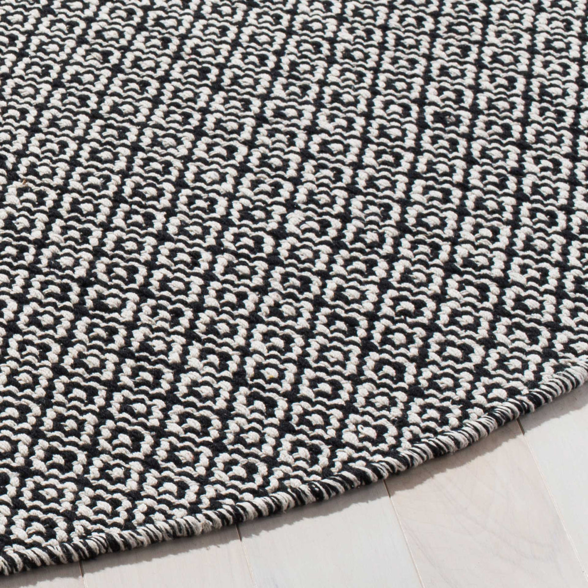 Black and ivory woven motifs meet a neatly finished, curved rug edge