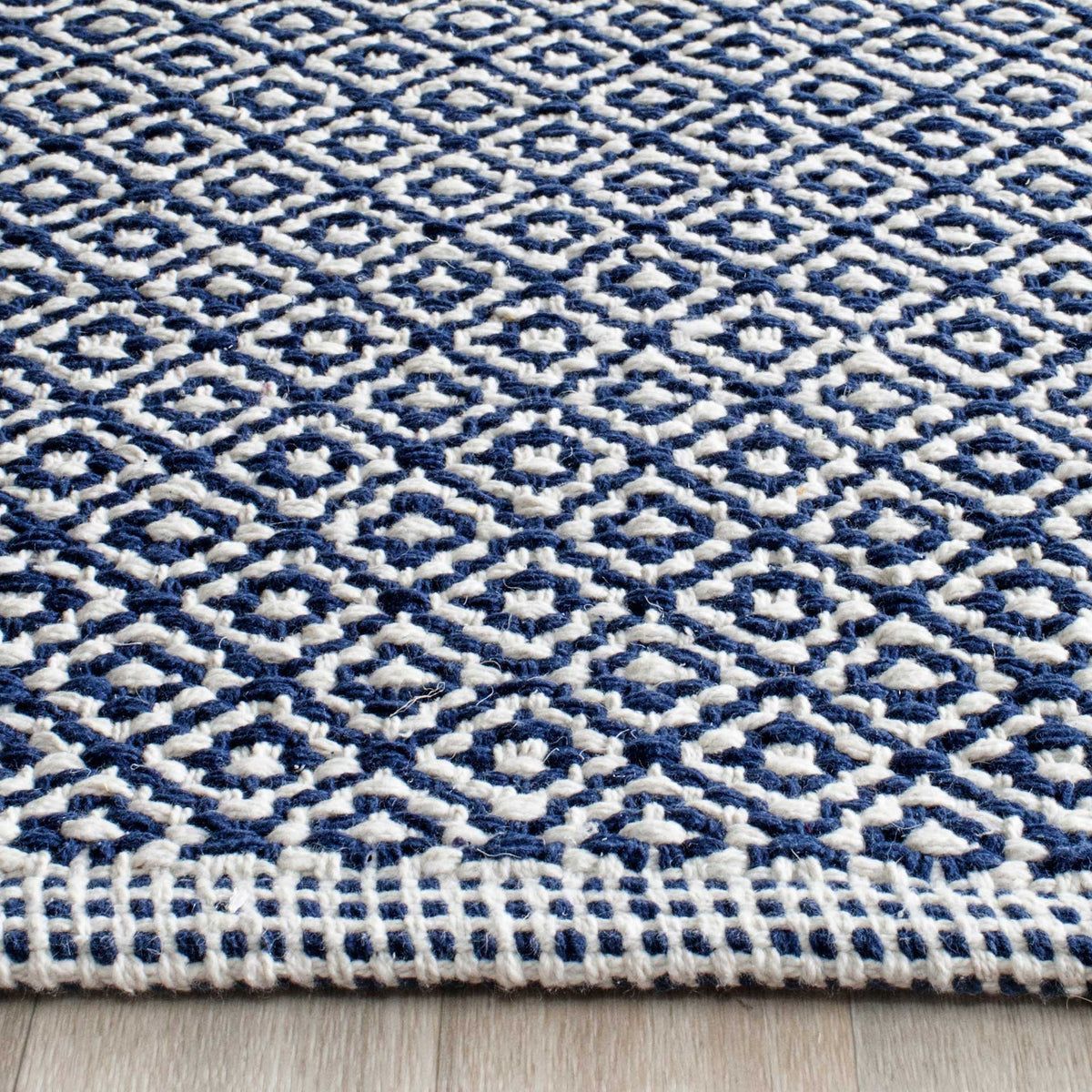 Textured navy and ivory cotton yarns form small diamonds above a neatly woven edge.