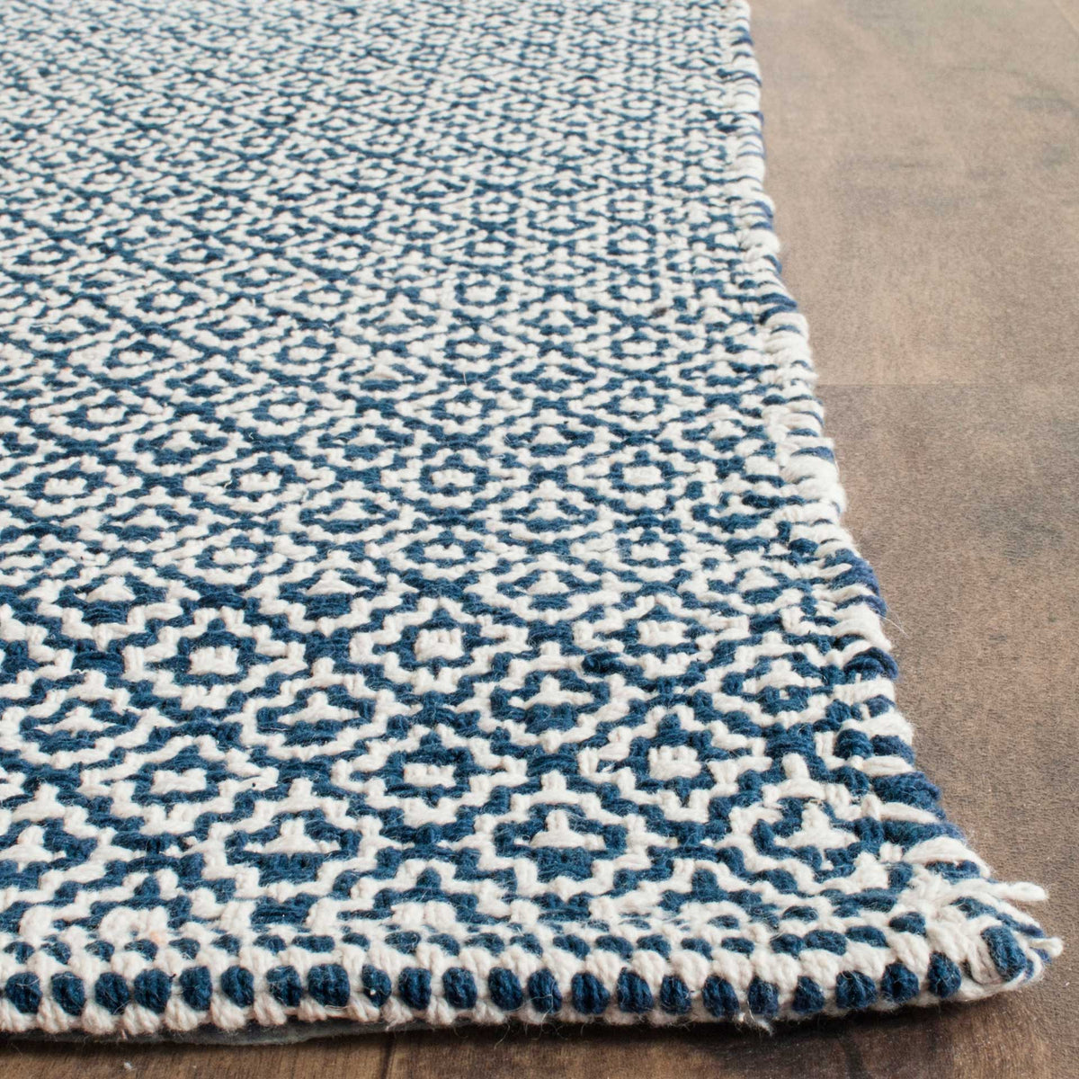 Navy and ivory diamonds meet a wrapped edge and textured corner on this cotton rug.