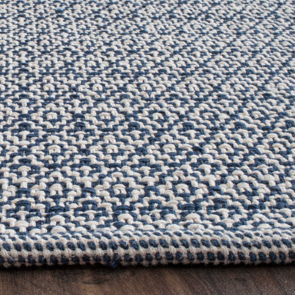 Dense navy and ivory weaving shows tactile diamond motifs and a neatly bound edge.