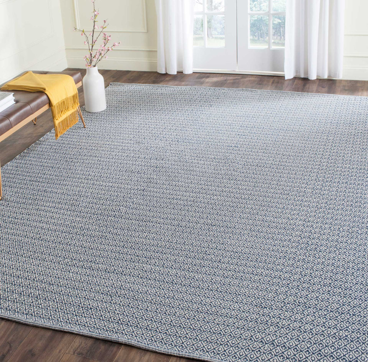 An ivory and navy geometric rug adds woven detail and strong contrast to the floor.