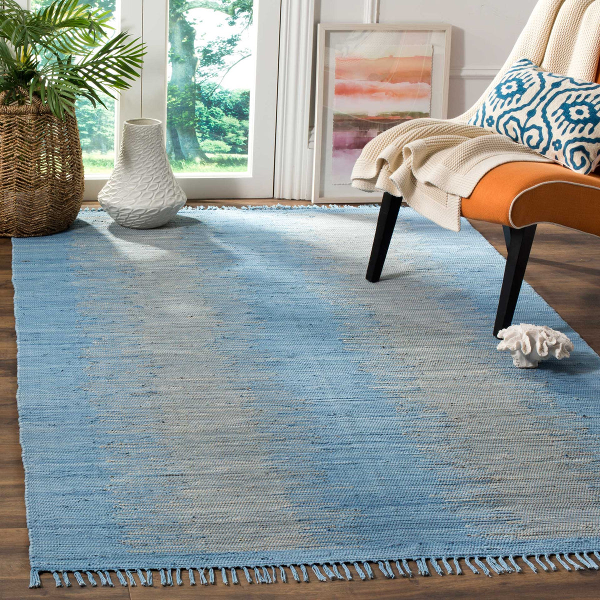 Pale blue and gray woven bands add gentle texture to a fringed cotton rug