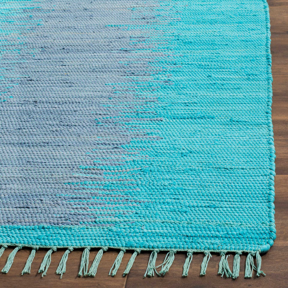 Turquoise and gray cotton strands interlace at a neatly bound corner with knotted fringe