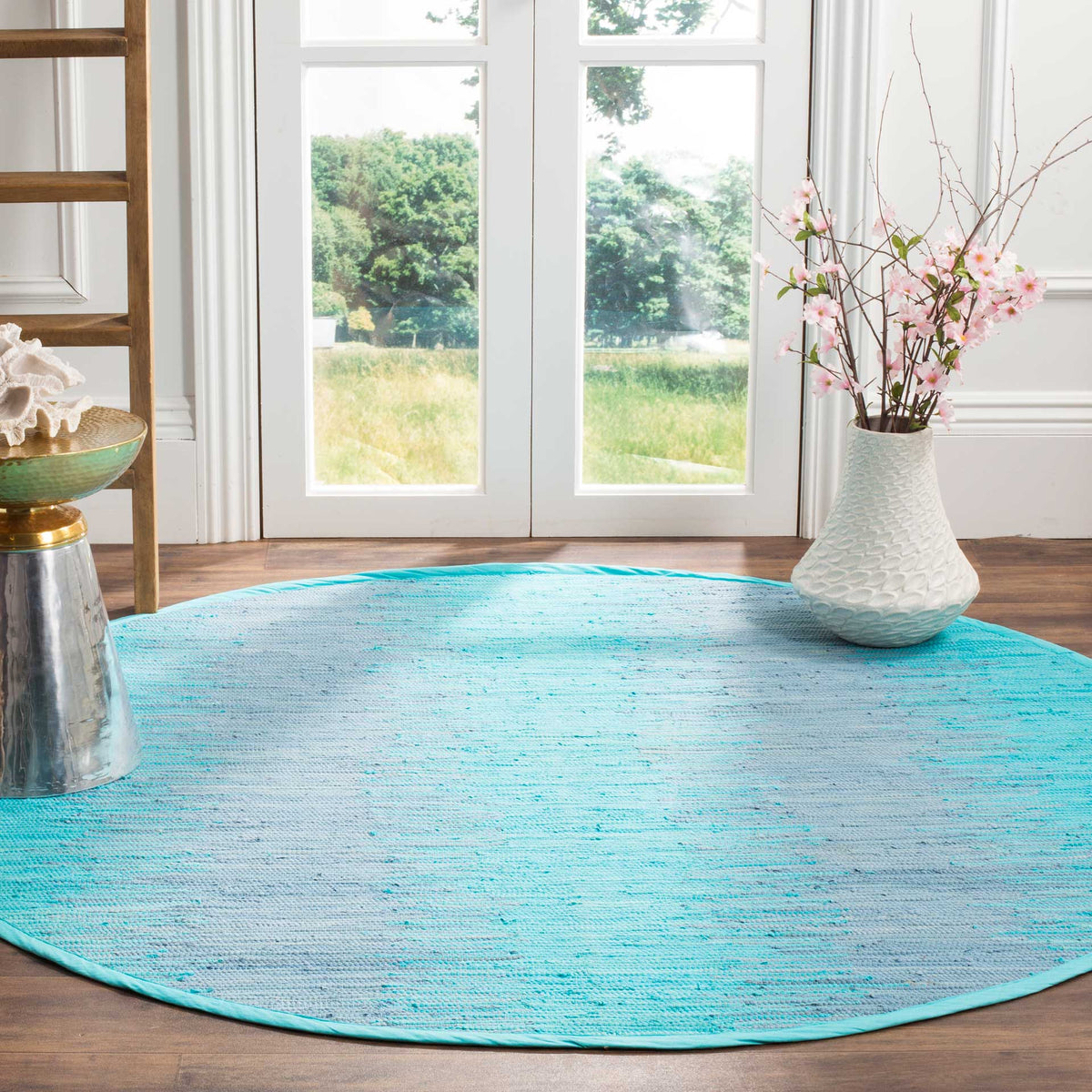 Cool turquoise hues and pale streaks bring a breezy feel to this round cotton rug