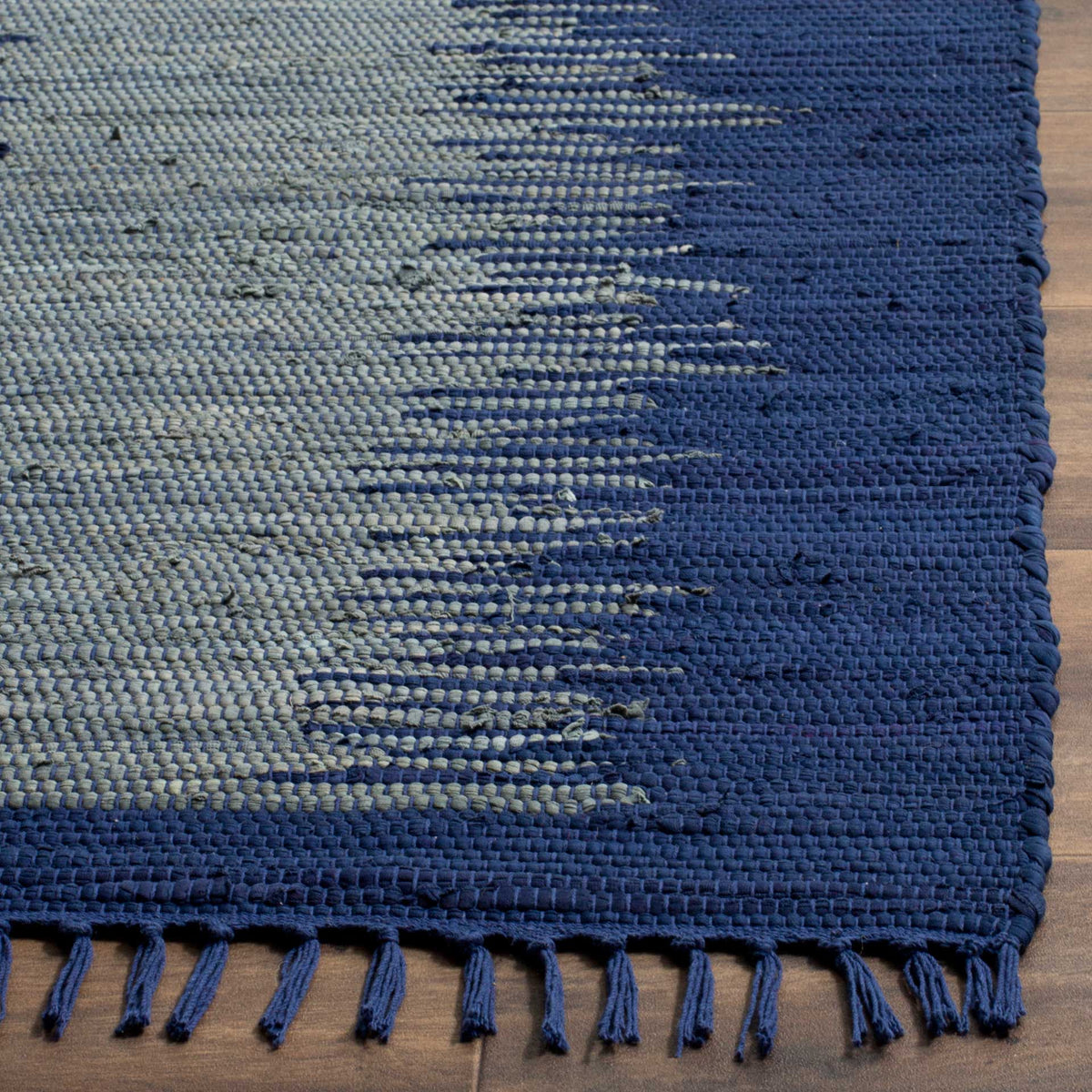 Navy and light blue-gray threads reveal rich woven texture beside knotted fringe