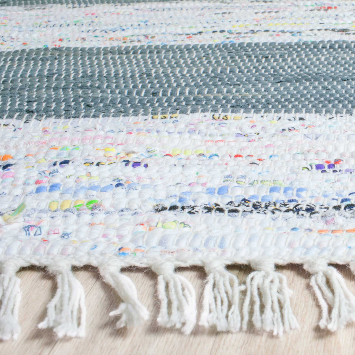 Soft fringe borders thick ivory and gray stripes woven with playful bits of color.