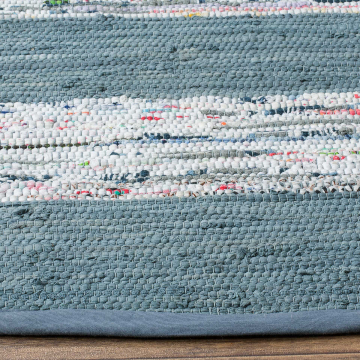 Handwoven cotton texture blends blue-gray yarns, colorful flecks, and a neatly bound edge.