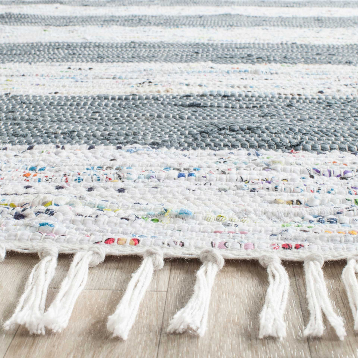 Raised cotton loops, colorful yarn flecks, and loose fringe add character to the gray and ivory weave.