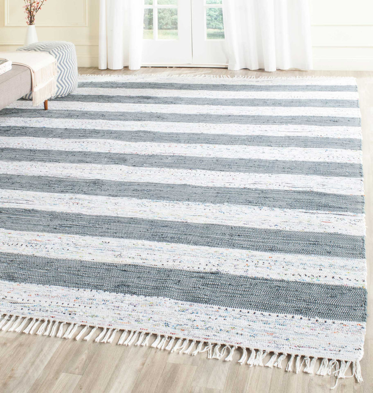 Wide gray and ivory stripes bring relaxed pattern to a low-profile cotton rug with fringe.